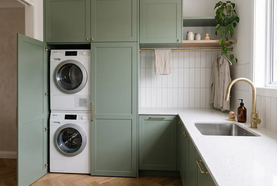 Compact renovated laundry with stacked appliances and sage cabinetry